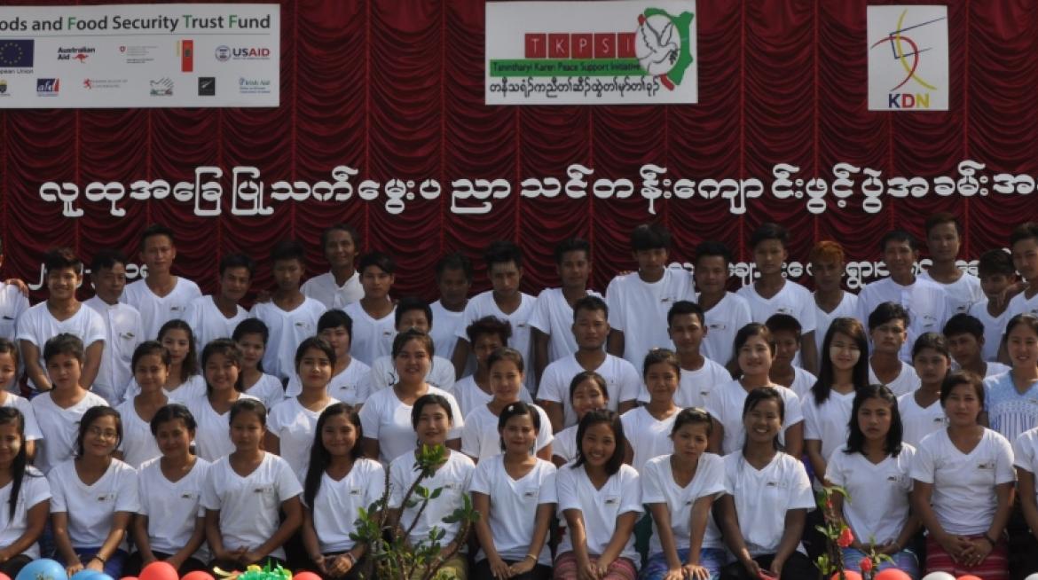 All students from the first cohort pose on stage